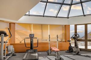 a gym with treadmills and ellipticals in a room with windows at AC Hotel Genova by Marriott in Genoa