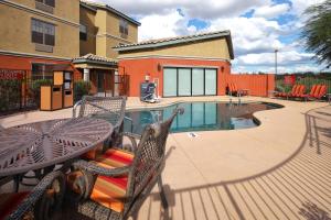 TownePlace Suites Tucson في توسان: فناء مع طاولة وكراسي بجوار حمام سباحة