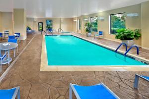 una piscina en una habitación de hotel con sillas y mesa en TownePlace Suites by Marriott Albany Downtown/Medical Center, en Albany