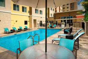 a pool with chairs and a table with an umbrella at Residence Inn by Marriott Miami Airport West/Doral in Miami