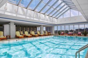 a large swimming pool with chairs and a glass ceiling at The Opus Westchester, Autograph Collection in White Plains