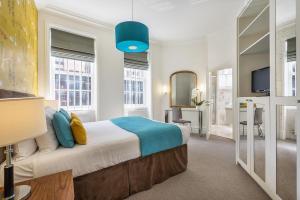 1 dormitorio con 1 cama grande y luz azul en Chelsea - Sloane Avenue by Viridian Apartments, en Londres