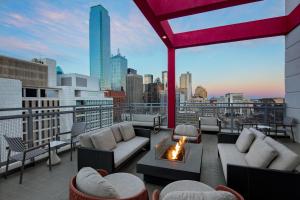 Courtyard by Marriott Dallas Downtown/Reunion District في دالاس: شرفة مع أرائك ومدفأة على مبنى