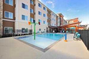 a pool with a playground in front of a building at Residence Inn by Marriott Houston Tomball in Tomball