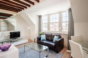 a living room with a leather couch and a tv at Chelsea - Sloane Avenue by Viridian Apartments in London