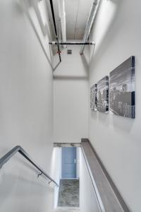 un escalier dans une chambre blanche avec deux photos sur le mur dans l'établissement Sable 71 - loft, à Minneapolis
