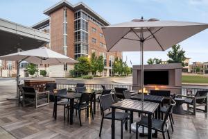 um pátio com mesas e cadeiras e um guarda-sol em AC Hotel by Marriott Pittsburgh Southpointe em Canonsburg