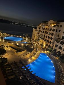 a large pool with blue lights in a city at night at Samarah Resort D44 in Sowayma