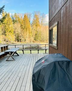 eine Holzterrasse mit einem Picknicktisch und einer Bank in der Unterkunft Waterfront Cabin at White Pass and Mount Rainier National Park in Packwood