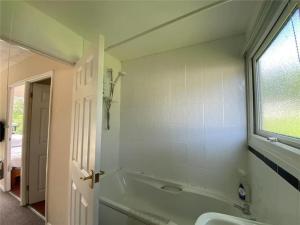 a bathroom with a tub and a sink and a window at 15 The Drive, Penstowe Holiday Park, Kilkhampton, Bude, Cornwall in Bude