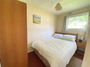 a bedroom with a bed with white sheets and a window at 15 The Drive, Penstowe Holiday Park, Kilkhampton, Bude, Cornwall in Bude