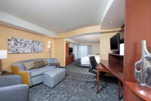 una camera d'albergo con divano, letto e scrivania di Courtyard Milwaukee Airport a Milwaukee