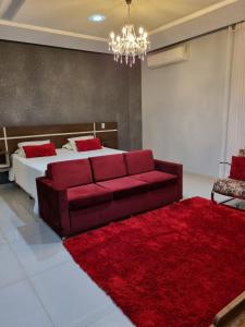 1 dormitorio con sofá rojo y 1 cama con alfombra roja en Hotel e Locadora Vizon en Vilhena