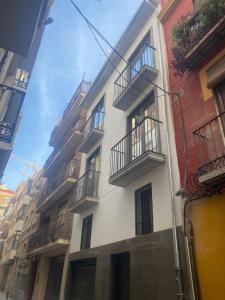 a tall white building with balconies on a street at Casa SanPau in Granada