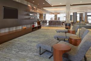 a lobby with a waiting area with chairs and a tv at Courtyard by Marriott Kingston Highway 401 in Kingston