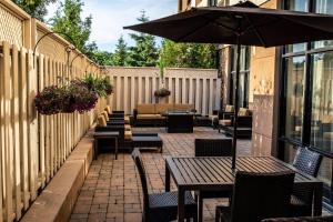 a patio with tables and chairs and an umbrella at Courtyard by Marriott Kingston Highway 401 in Kingston