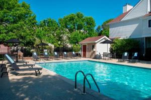 a swimming pool with chairs and umbrellas next to a house at Residence Inn Philadelphia Valley Forge in Berwyn