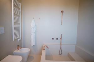 La salle de bains blanche est pourvue d'une douche et de toilettes. dans l'établissement Masseria Egnazia - Epoca Collection, à Savelletri di Fasano