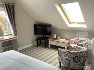 1 dormitorio con 1 cama, 1 silla y TV en New Overlander Inn, en Tenby