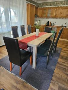 mesa de comedor con sillas negras y mesa de madera en Fenyves Apartman en Tiszafüred