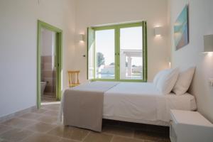 a bedroom with a white bed and a large window at Masseria Egnazia - Epoca Collection in Savelletri di Fasano