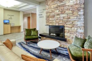 a lobby with a fireplace and chairs and a table at Fairfield Inn & Suites Woodbridge in Avenel