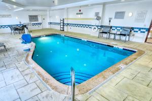 una piscina en una habitación de hotel con sillas y mesas en Fairfield Inn & Suites Woodbridge, en Avenel