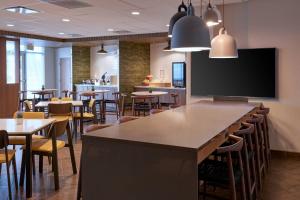 Fairfield Inn & Suites by Marriott Midland في ميدلاند: مطعم بطاولات وكراسي وتلفزيون بشاشة مسطحة