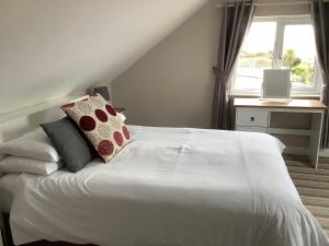 Un dormitorio con una cama blanca con almohadas y una ventana en New Overlander Inn, en Tenby