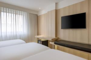 a hotel room with two beds and a flat screen tv at AC Hotel Córdoba by Marriott in Córdoba