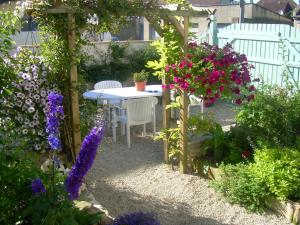 un giardino con tavolo e alcuni fiori di Chambres Chez Mounie ad Arromanches-les-Bains