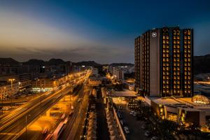 een uitzicht op een stad in de nacht met een hoog gebouw bij Sheraton Oman Hotel in Muscat