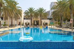 una grande piscina con palme e fontana di Sheraton Oman Hotel a Mascate