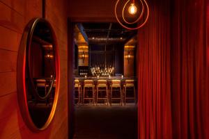 a room with a bar with a mirror and a red curtain at MOXY NYC Times Square in New York