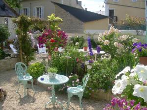 a garden with a table and chairs and flowers at Chambres Chez Mounie in Arromanches-les-Bains