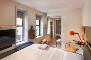 a bedroom with a white bed and a living room at MOXY NYC Times Square in New York