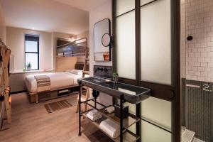 a bathroom with a sink and a bed in a room at MOXY NYC Times Square in New York