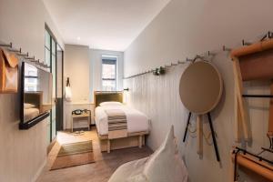 a small bedroom with a bed and a mirror at MOXY NYC Times Square in New York