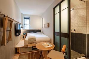 a bedroom with a bed and a table and a shower at MOXY NYC Times Square in New York