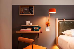 a bedroom with a table with a clock and a bed at MOXY NYC Times Square in New York