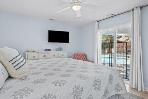 1 dormitorio con cama, TV y balcón en The Blue Lagoon, en Pine Knoll Shores