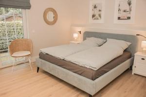 Un dormitorio con una cama, una silla y una ventana en Appartement salt mit Südterrasse, en Timmendorfer Strand