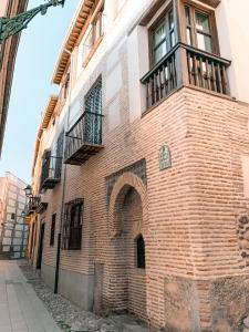 a brick building with a balcony on a street at Apartamentos en pleno centro, Aljibe Rodrigo del Campo 2C in Granada