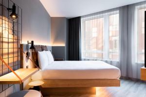 a bedroom with a bed and a large window at Moxy The Hague in The Hague