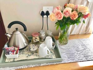 a tray with a tea pot and flowers on a table at Lavender Lane Cottage in Johannesburg