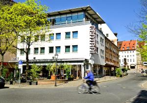 Um homem a andar de bicicleta numa rua em frente a um edifício. em Hotel Central em Nuremberga