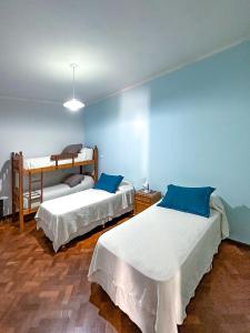 twee bedden in een kamer met blauwe muren bij El Oasis in Mendoza