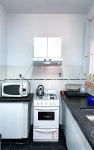 een witte keuken met een fornuis en een magnetron bij El Oasis in Mendoza