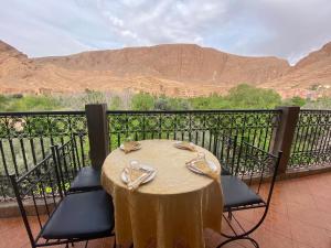 un tavolo e sedie su un balcone con vista sulle montagne di La Petite Gorge, Hôtel & Restaurant Todra Gorge a Tinerhir