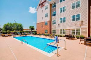 a pool in front of a hotel with tables and chairs at Residence Inn by Marriott Roanoke Airport in Roanoke